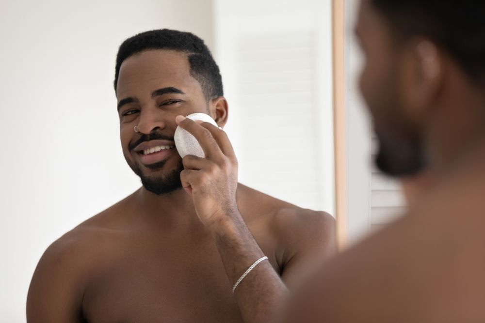 a shirtless man is washing his face in front of a mirror