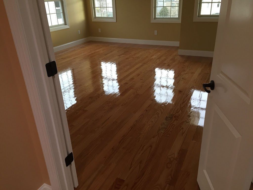 An empty room with hardwood floors and three windows