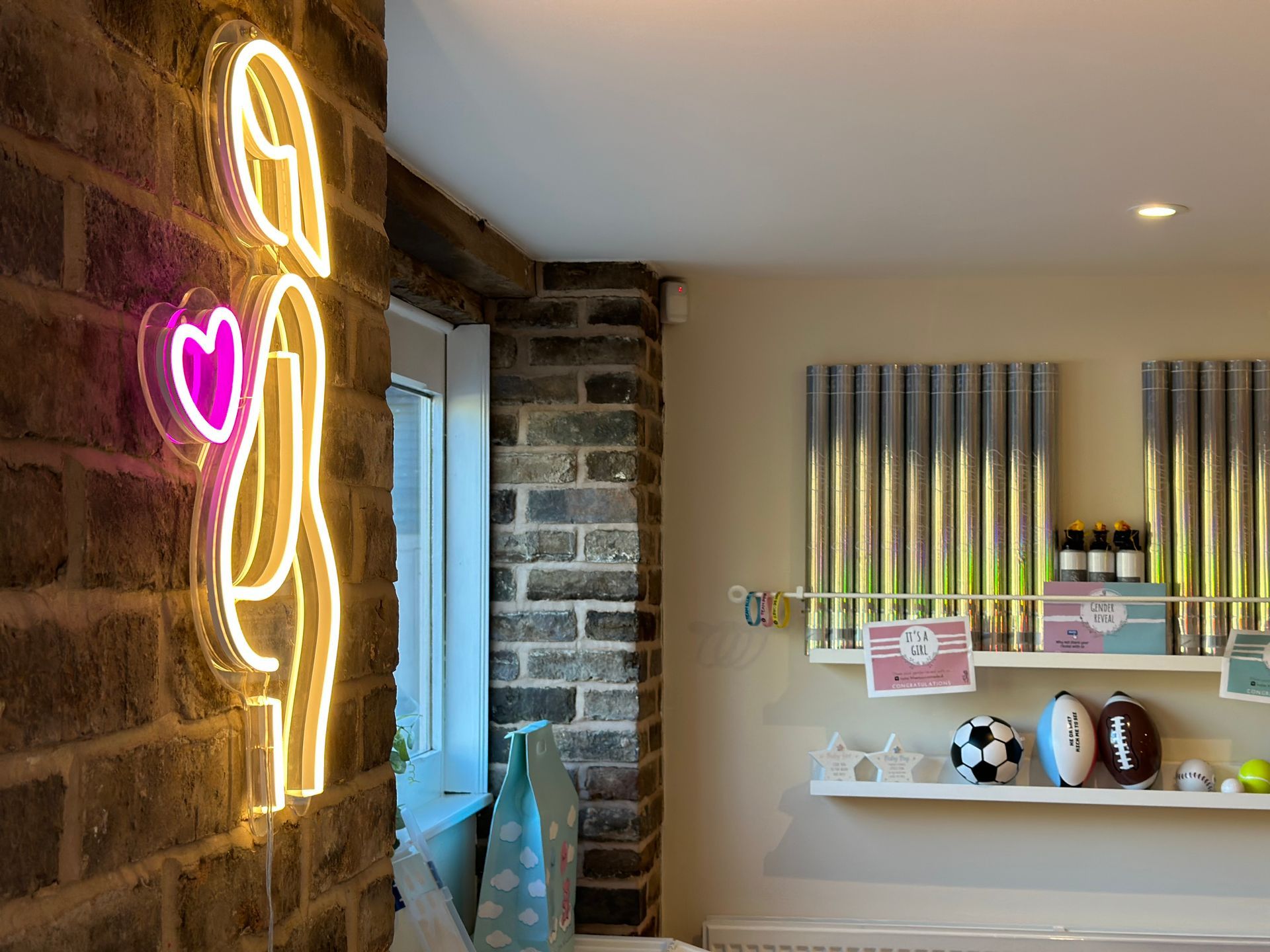 A room with a brick wall and a neon sign on the wall.