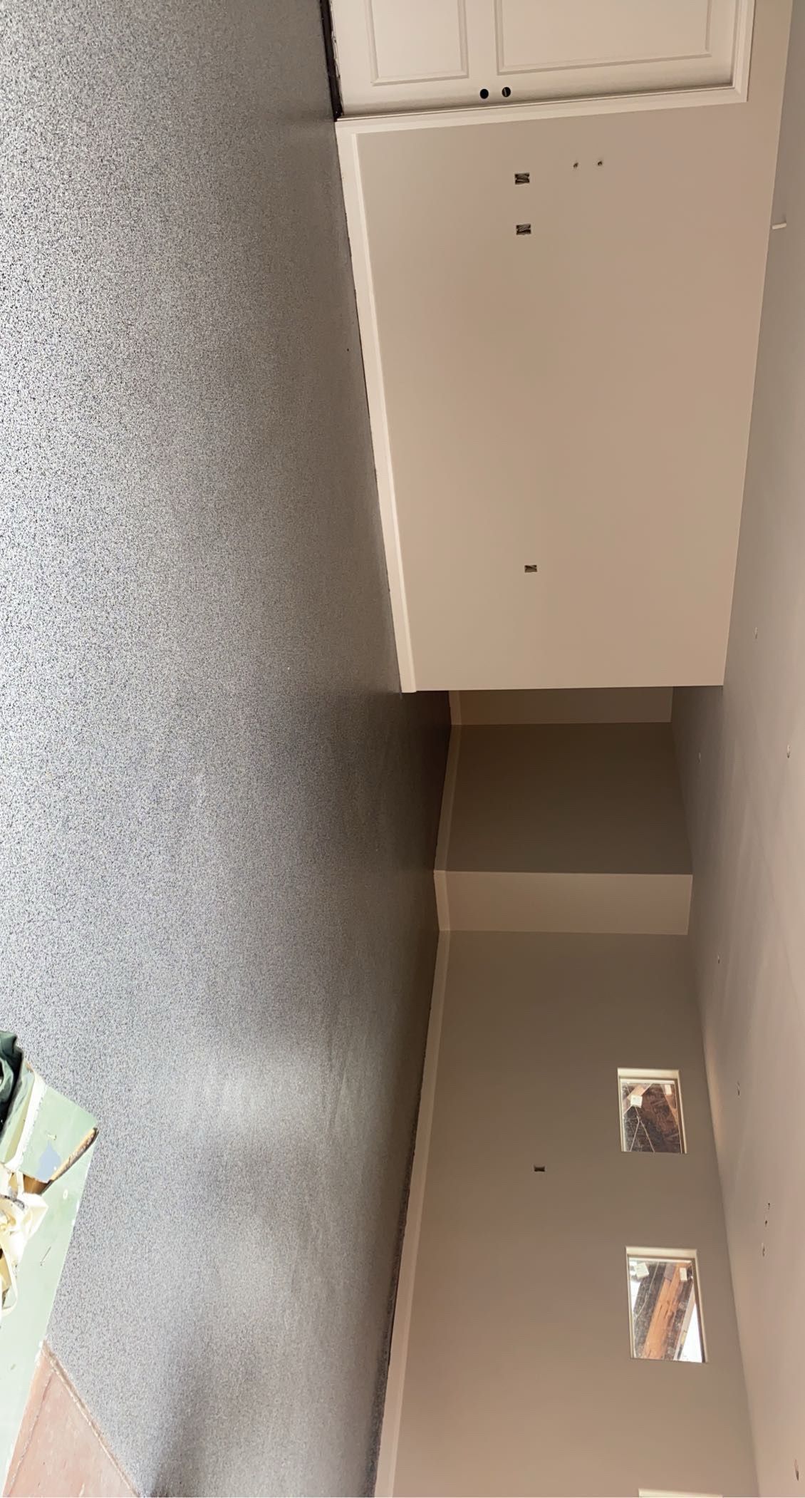 A white cabinet is sitting on top of a gray wall in a room.