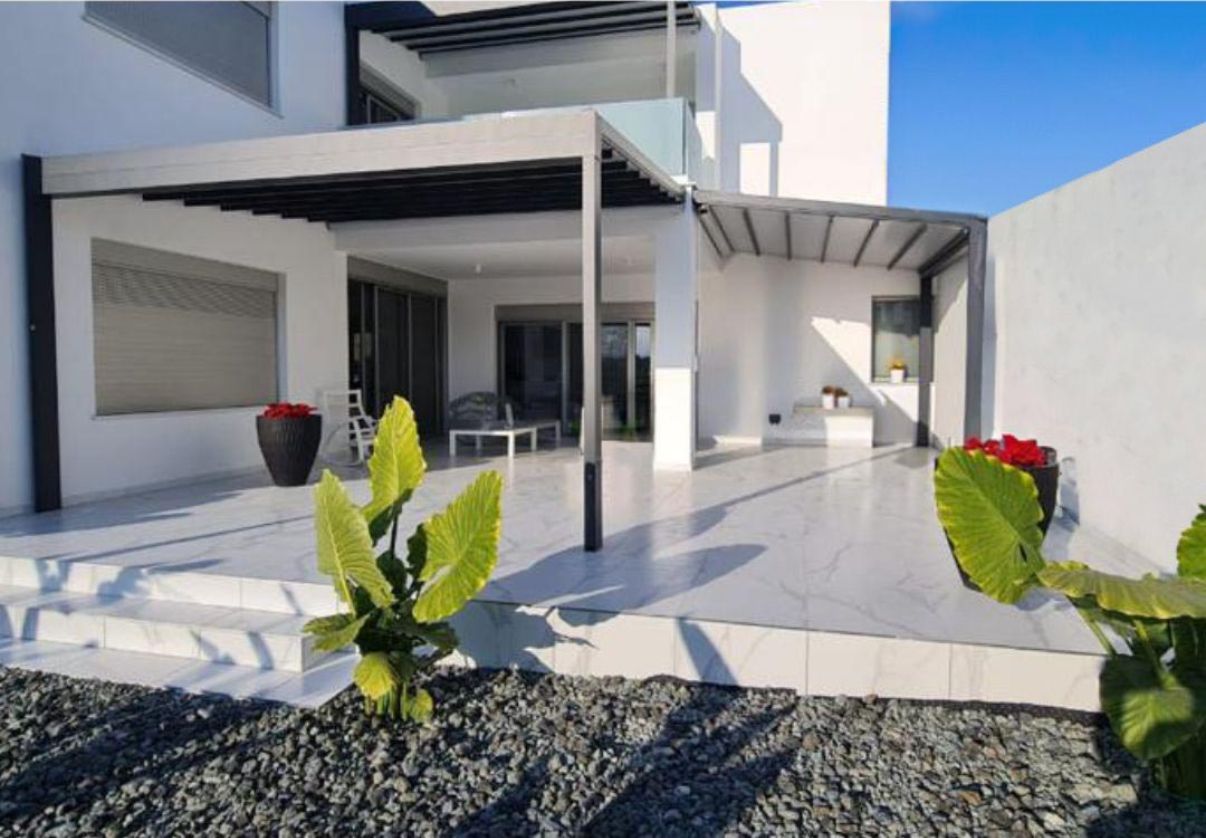 Una casa bianca con un patio e un pergolato