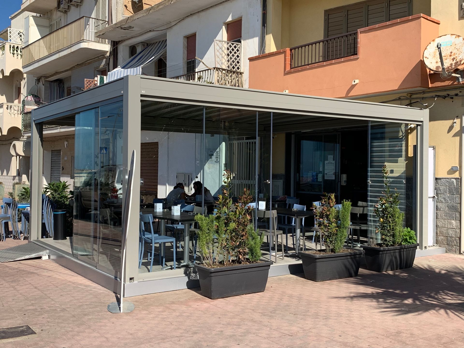 Un ristorante con tavoli e sedie sotto un pergolato di vetro.