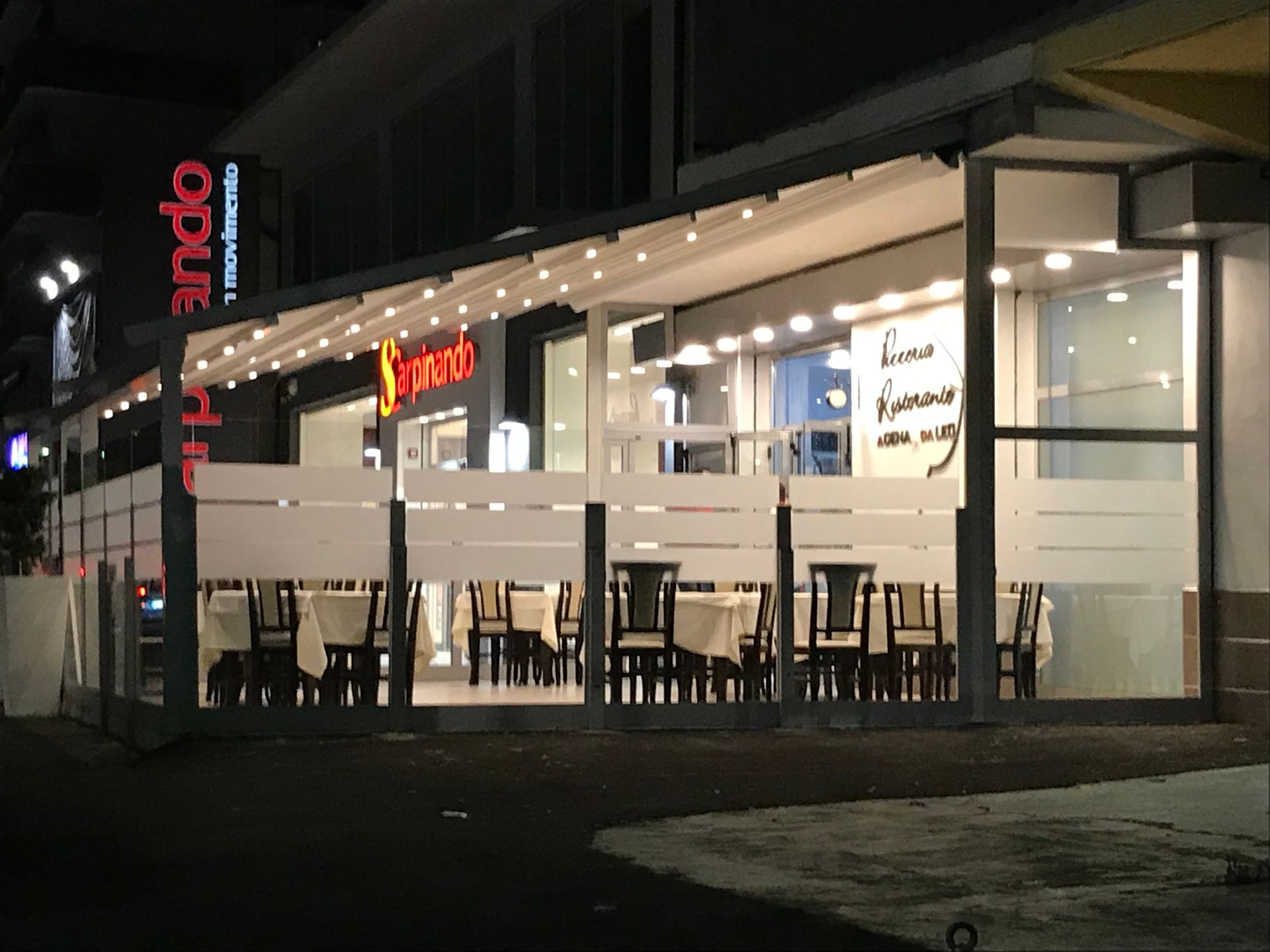 Un ristorante con tavoli e sedie è illuminato di notte