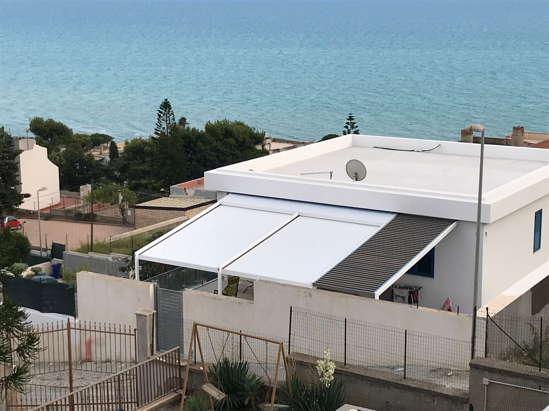 Una casa bianca con una tenda da sole bianca sul tetto che si affaccia sull'oceano.