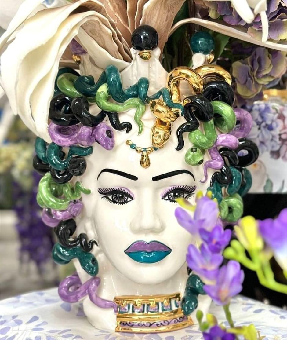 Un vaso con il volto di una donna e dei fiori sopra