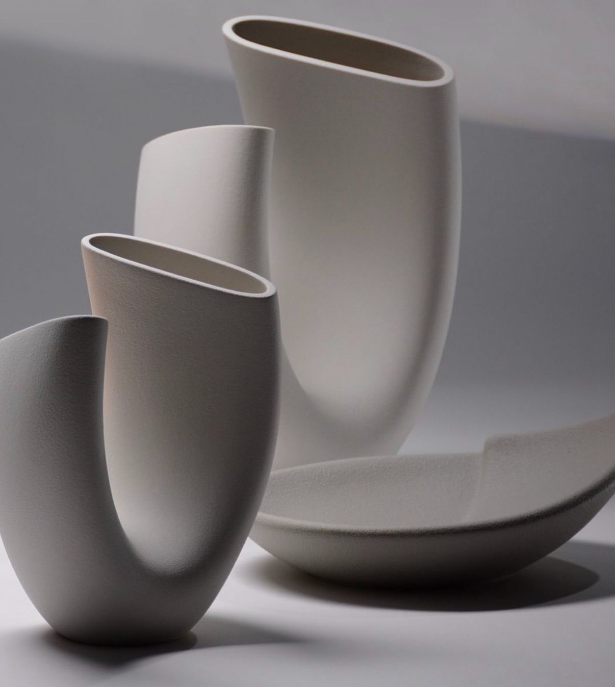 Tre vasi bianchi sono appoggiati uno accanto all'altro su un tavolo