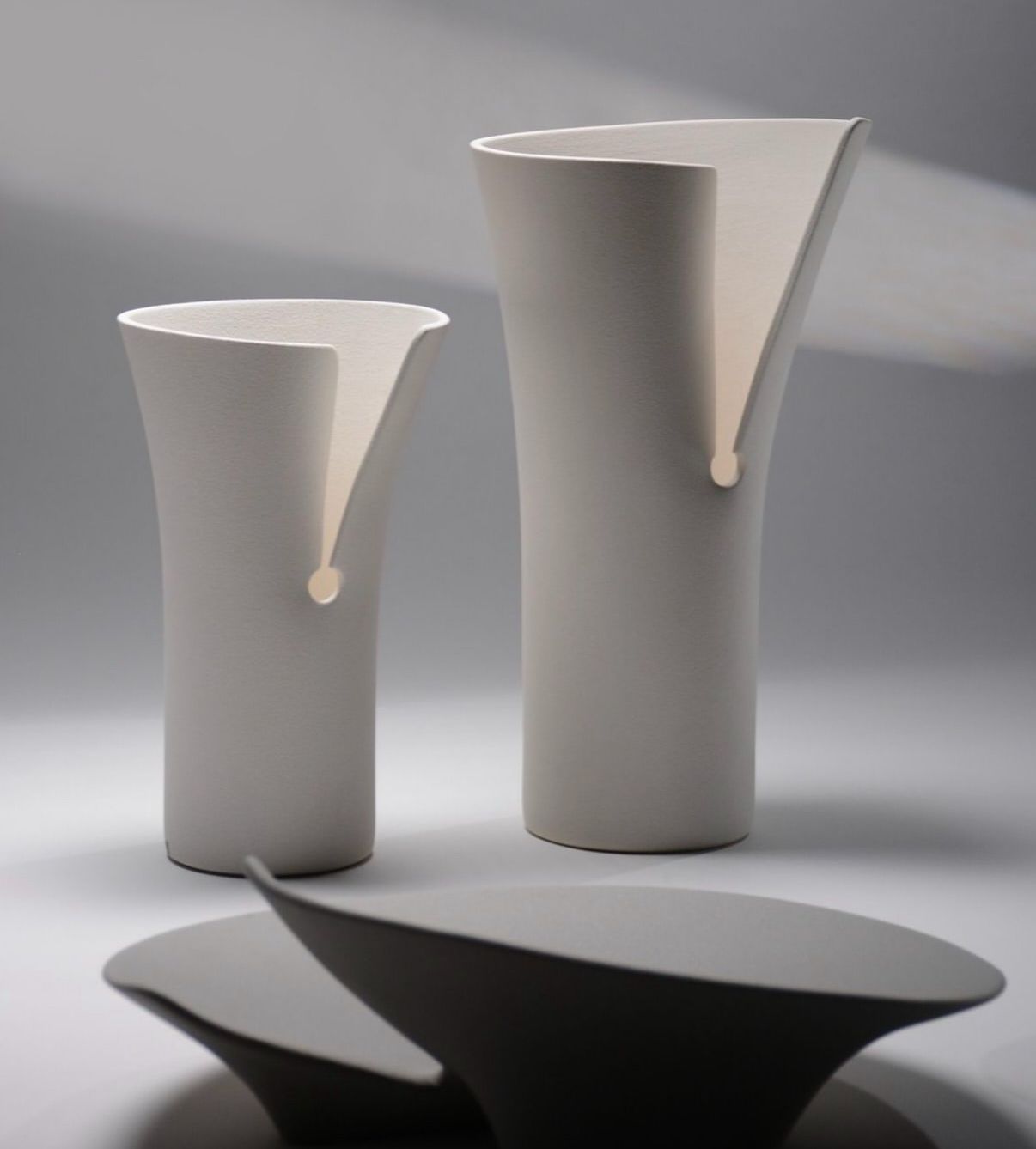 Due vasi bianchi e una ciotola nera su un tavolo