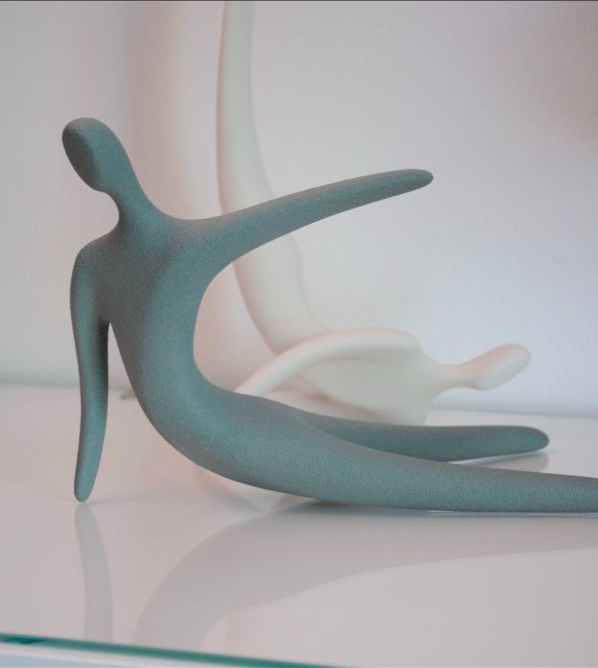 Una statua di una persona è seduta su un tavolo di vetro