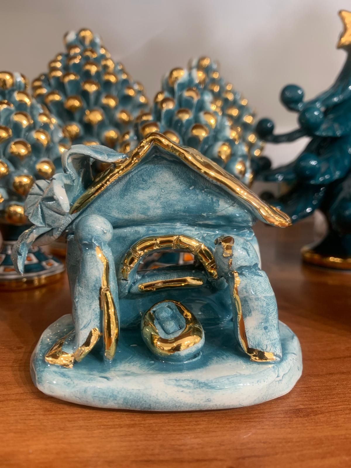 Una statuina del presepe blu e oro è seduta su un tavolo di legno.