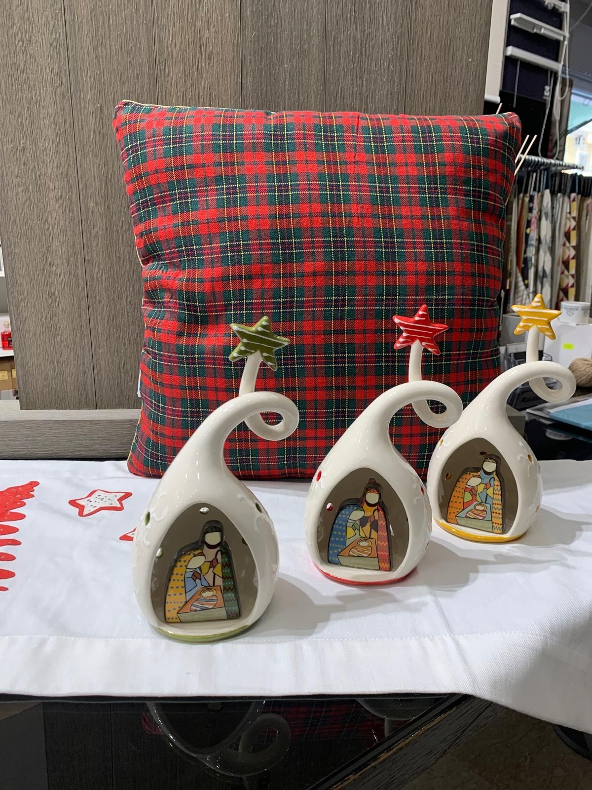 Tre decorazioni natalizie sono appoggiate su un tavolo accanto a un cuscino.