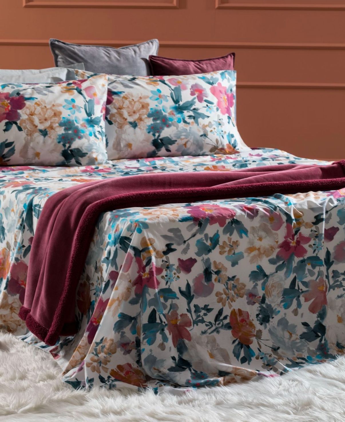 Un letto con un piumone floreale e dei cuscini.