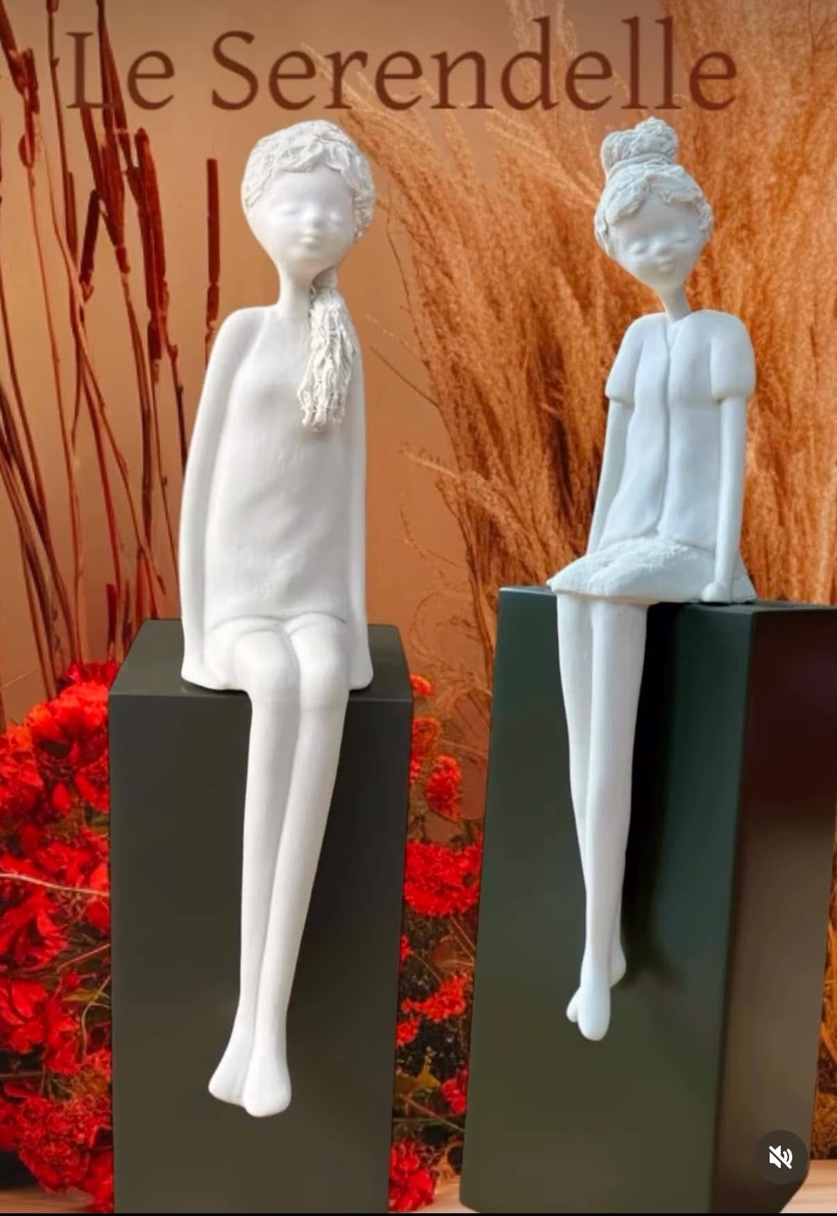 Un paio di statue di donne sedute su dei blocchi.