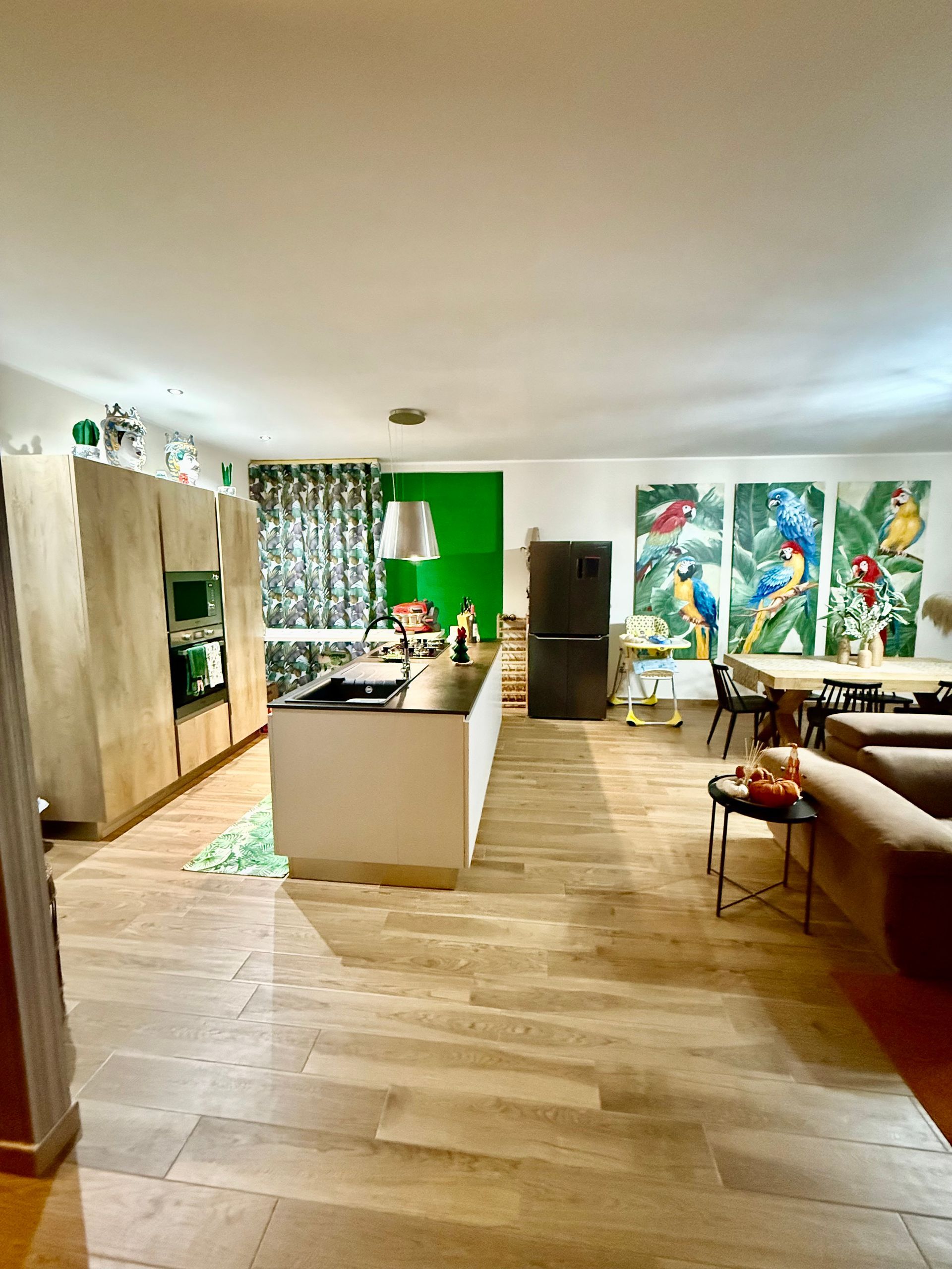 Un soggiorno pieno di mobili e una cucina con una parete verde.