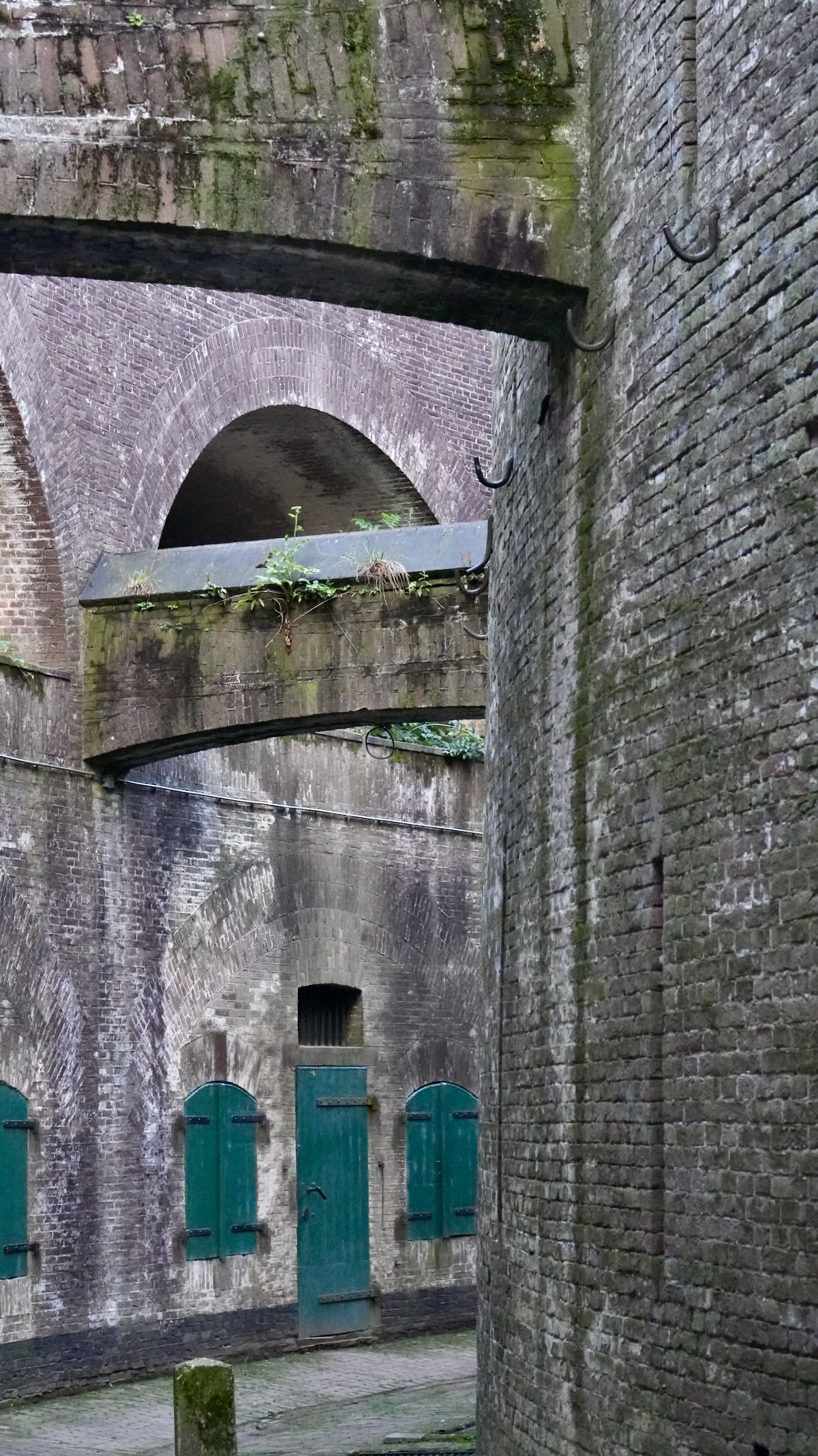 Een bakstenen gebouw met groene deuren en bogen.