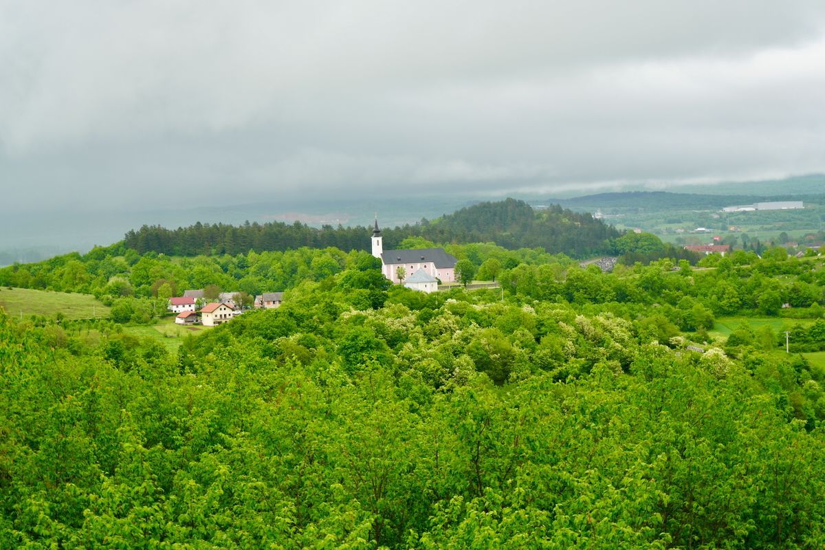 Crkva Uzvišenja Svetog Križa Een kerk staat op de top van een heuvel, omgeven door bomen.