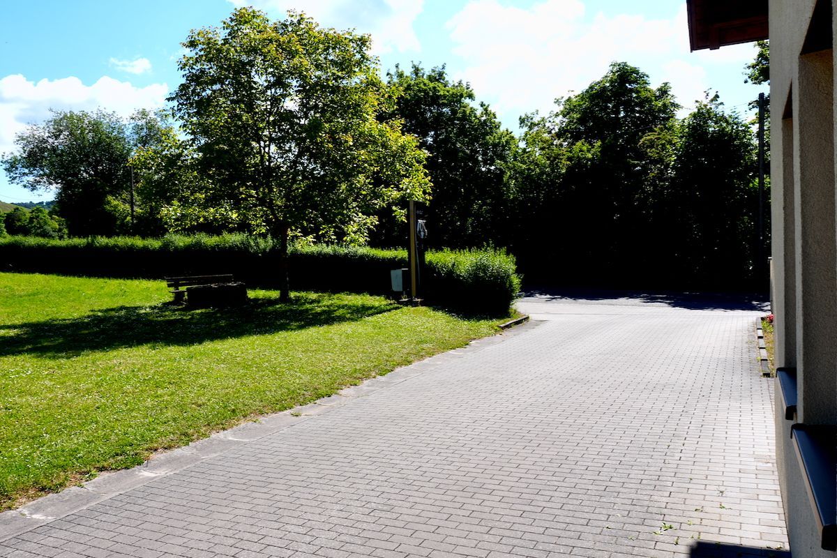 De in- en uitgang van de Cp Een oprit van baksteen die leidt naar een weelderig groen veld