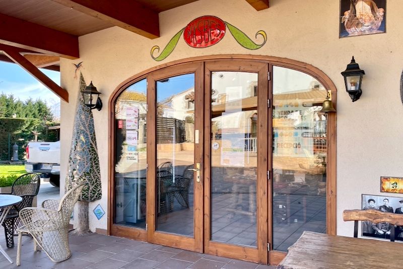 Gebogen houten deur naar een winkel, met glazen panelen. Een decoratief rood-groen ontwerp siert de deur.