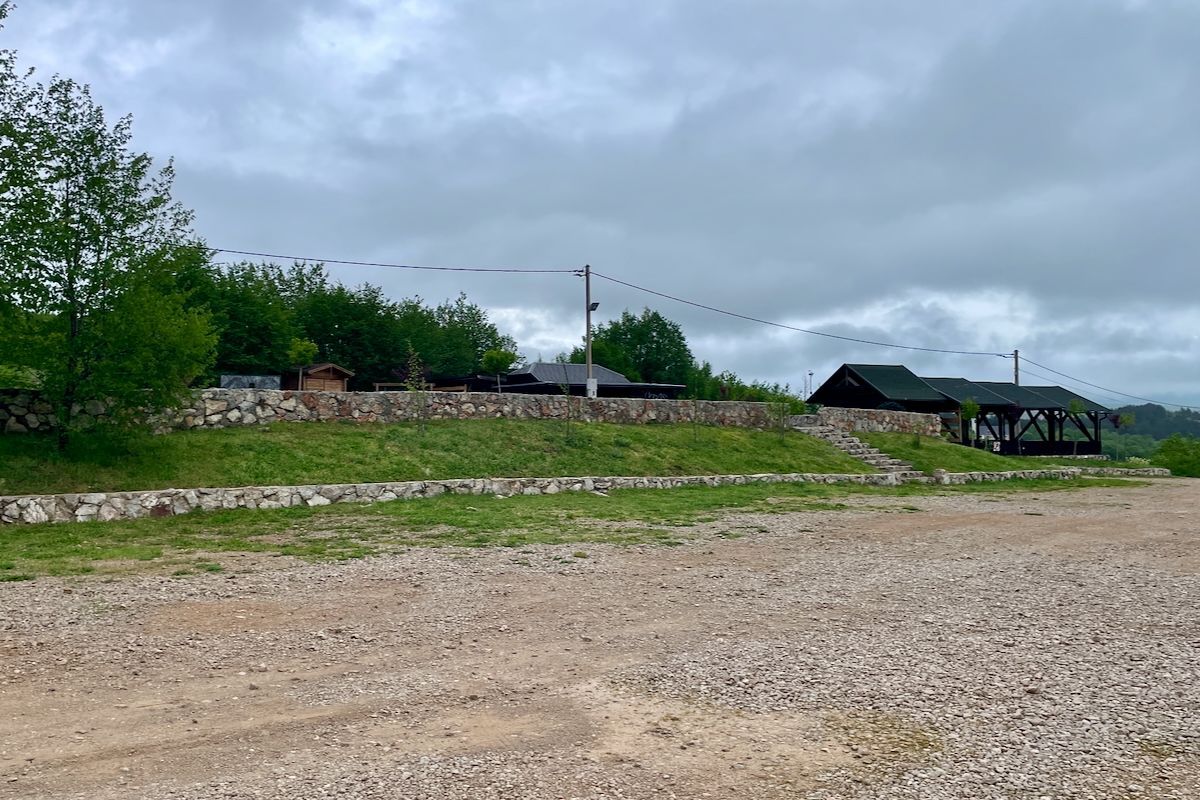 Pećinski park Grabovača Een grindweg met een huis op de achtergrond en bomen op de voorgrond.