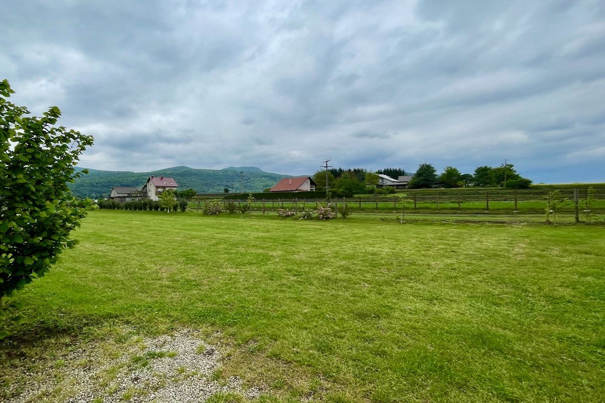 Het Kroatische platteland Een groot grasveld met een hek en een huis op de achtergrond.