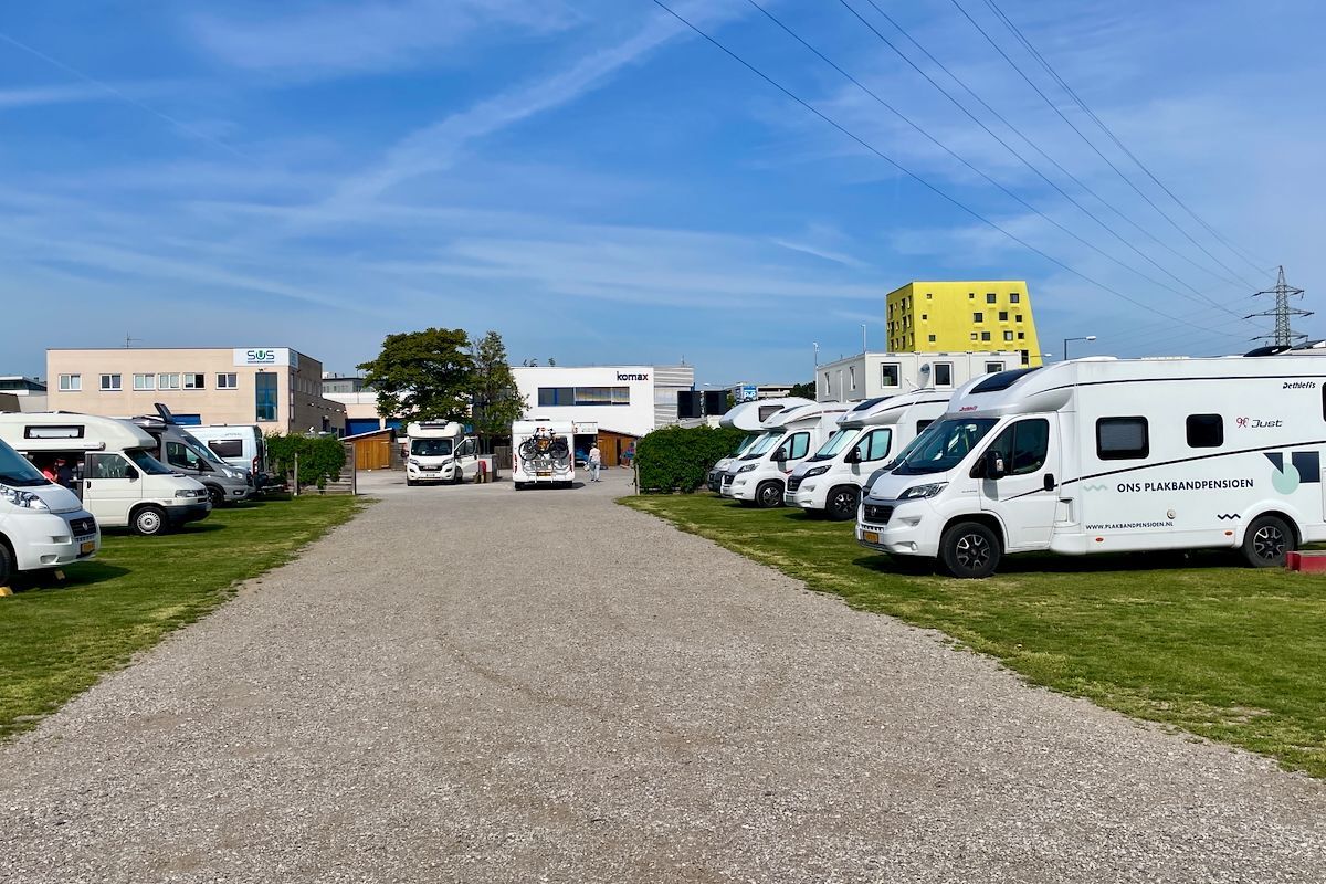 Reisemobil - Stellplatz Wien Een rij witte campers staat geparkeerd op een grindterrein.