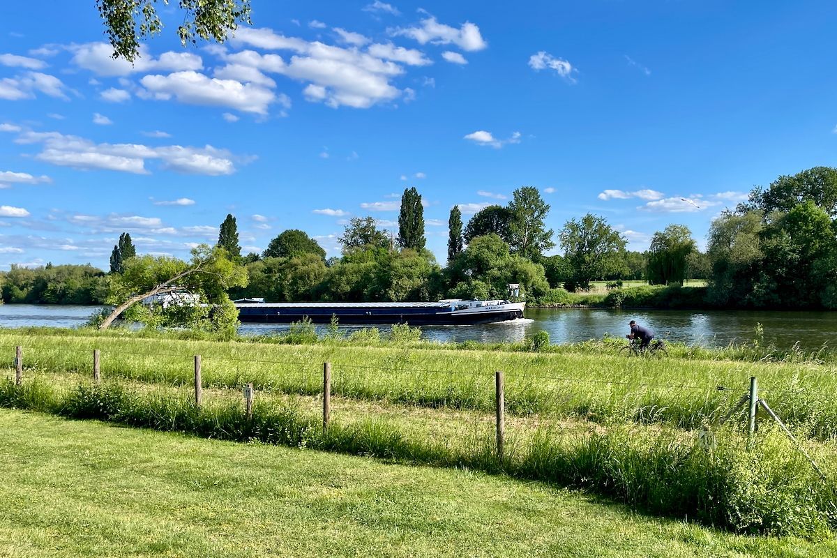Scheepvaart op de Main Een boot drijft op een rivier naast een grasveld.