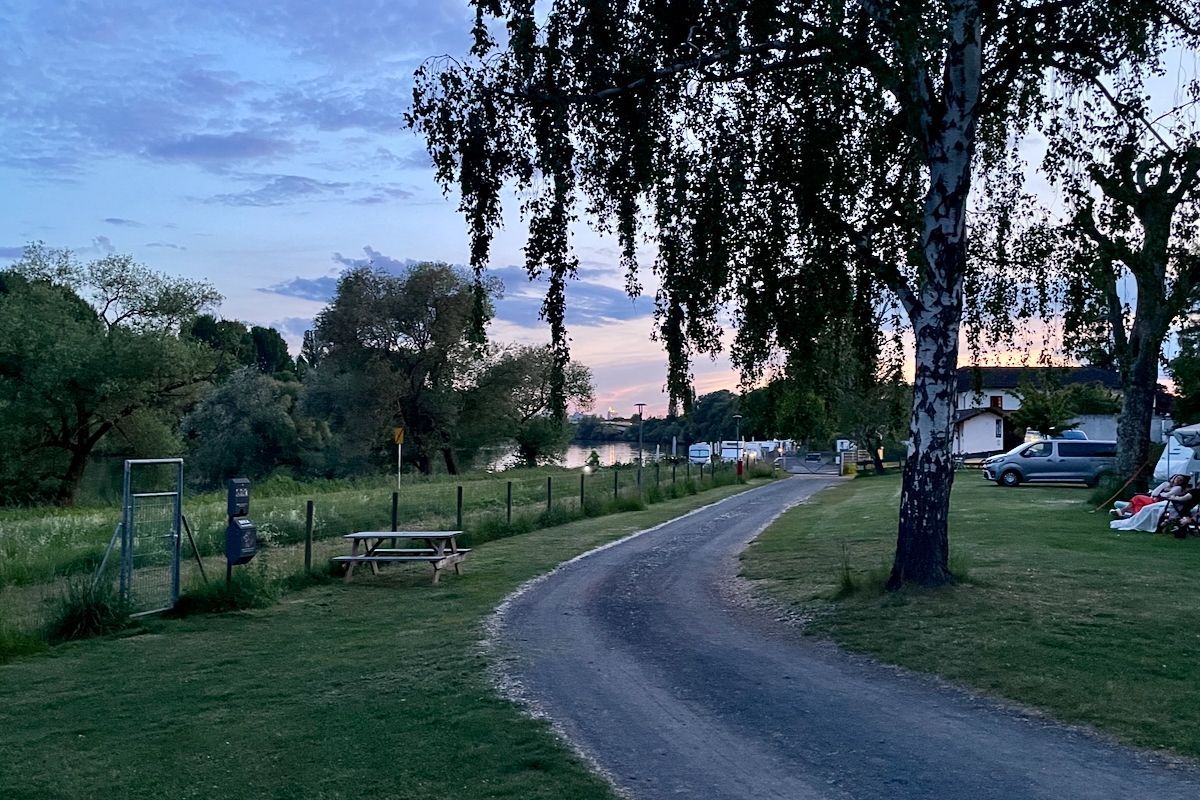 De avond valt - zicht op Frankfurt am Main Een onverharde weg door een grasveld met een picknicktafel.