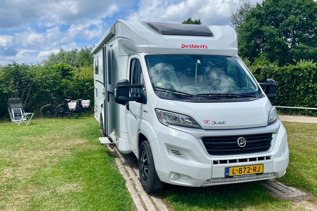 Ruime plek Een witte camper staat geparkeerd in een grasveld.