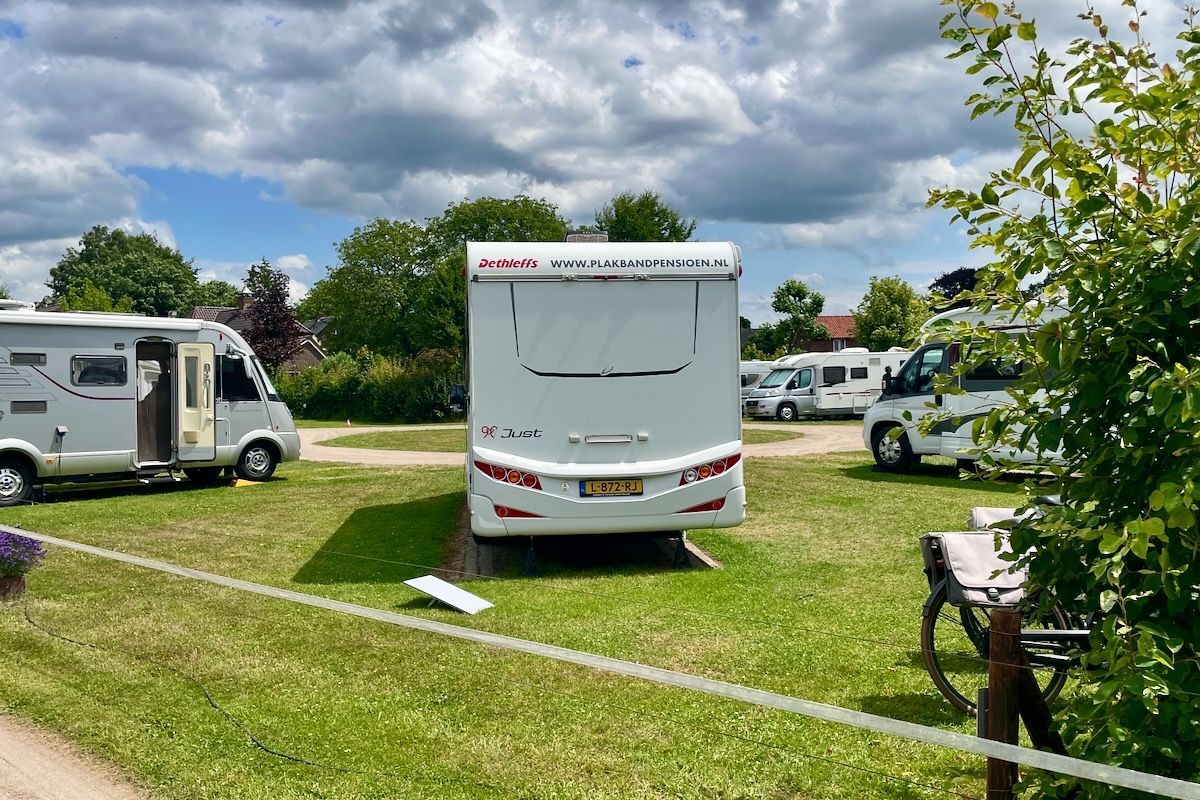 Op de kont Een witte camper staat geparkeerd in een grasveld.