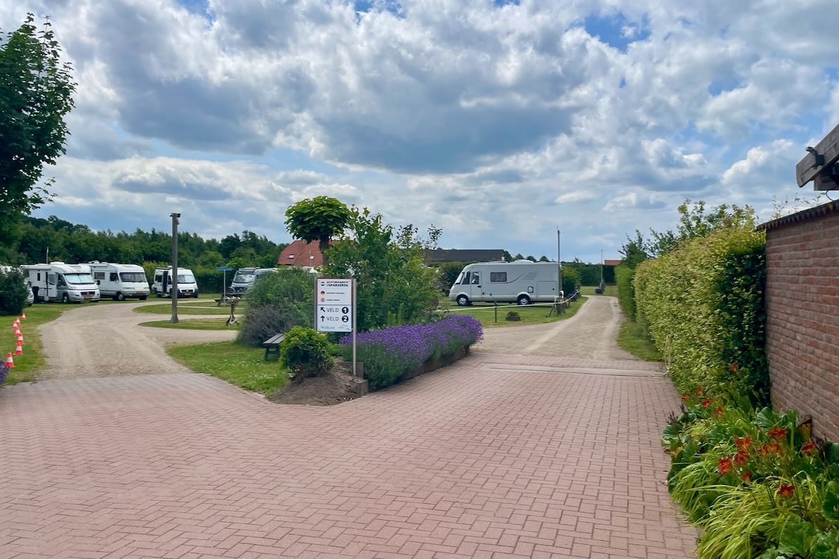 De camperplaats Landlust Een rij campers staat geparkeerd op een parkeerplaats.