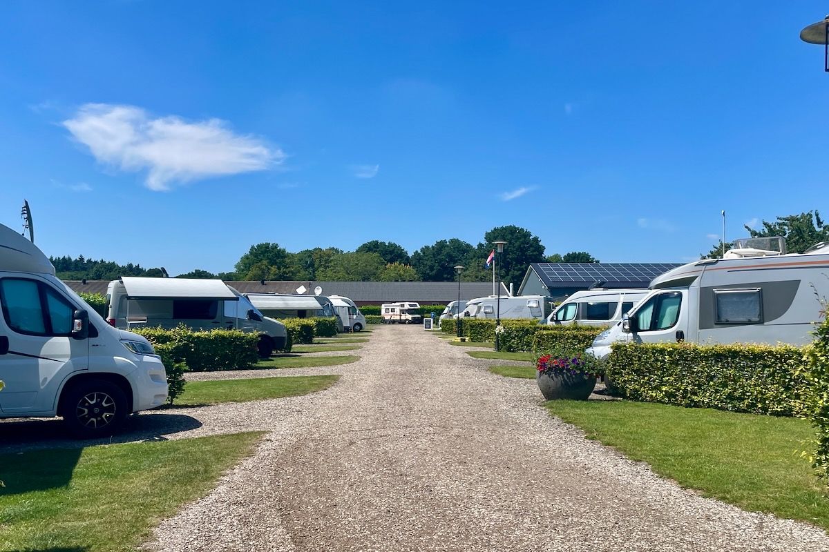 De overige deel) van de plekken Een rij campers geparkeerd langs een grindweg.