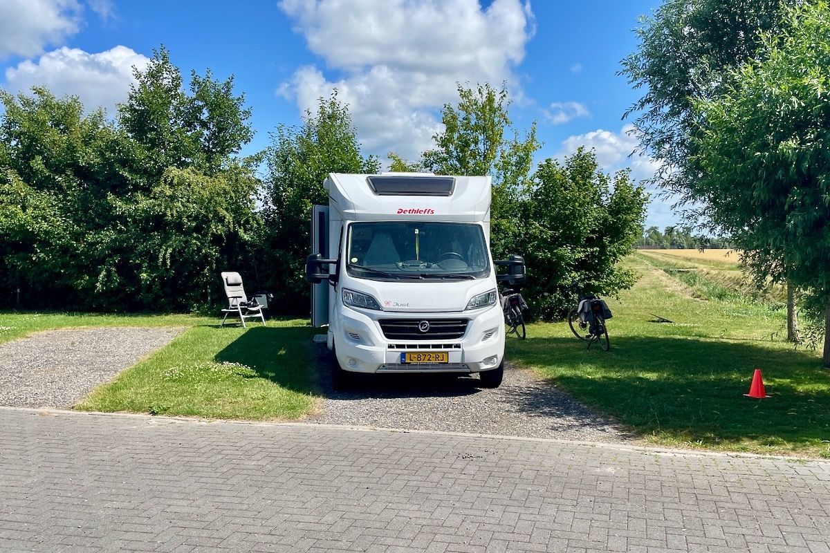 Een witte camper staat geparkeerd in een grasveld.