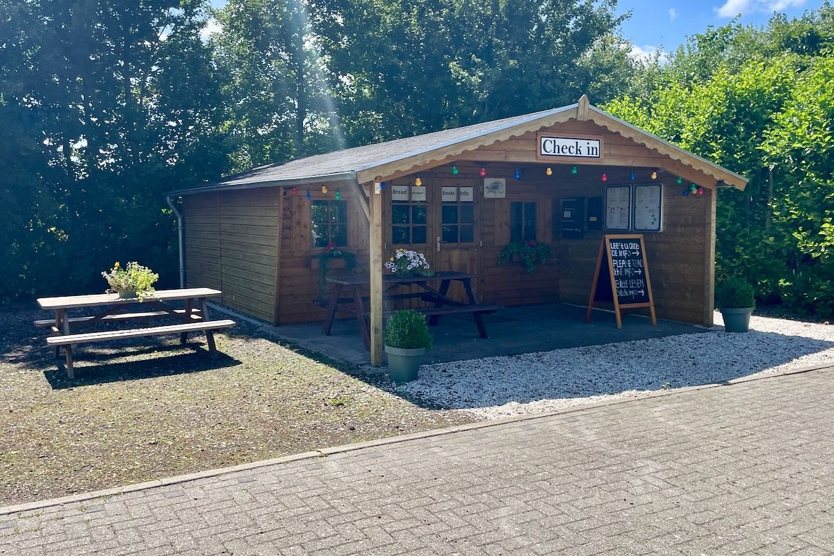 Een klein houten huisje met een picknicktafel ervoor.