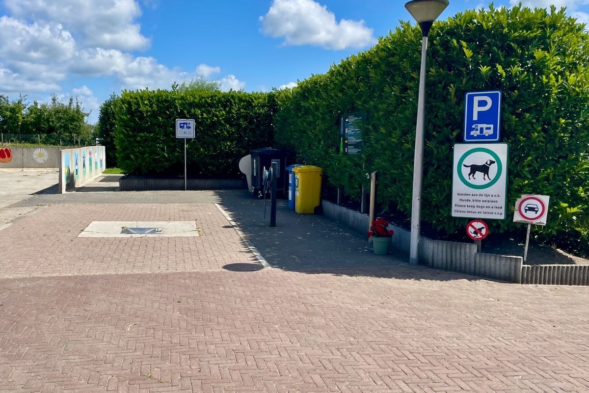 Een parkeerplaats met een bord waarop staat dat honden niet zijn toegestaan