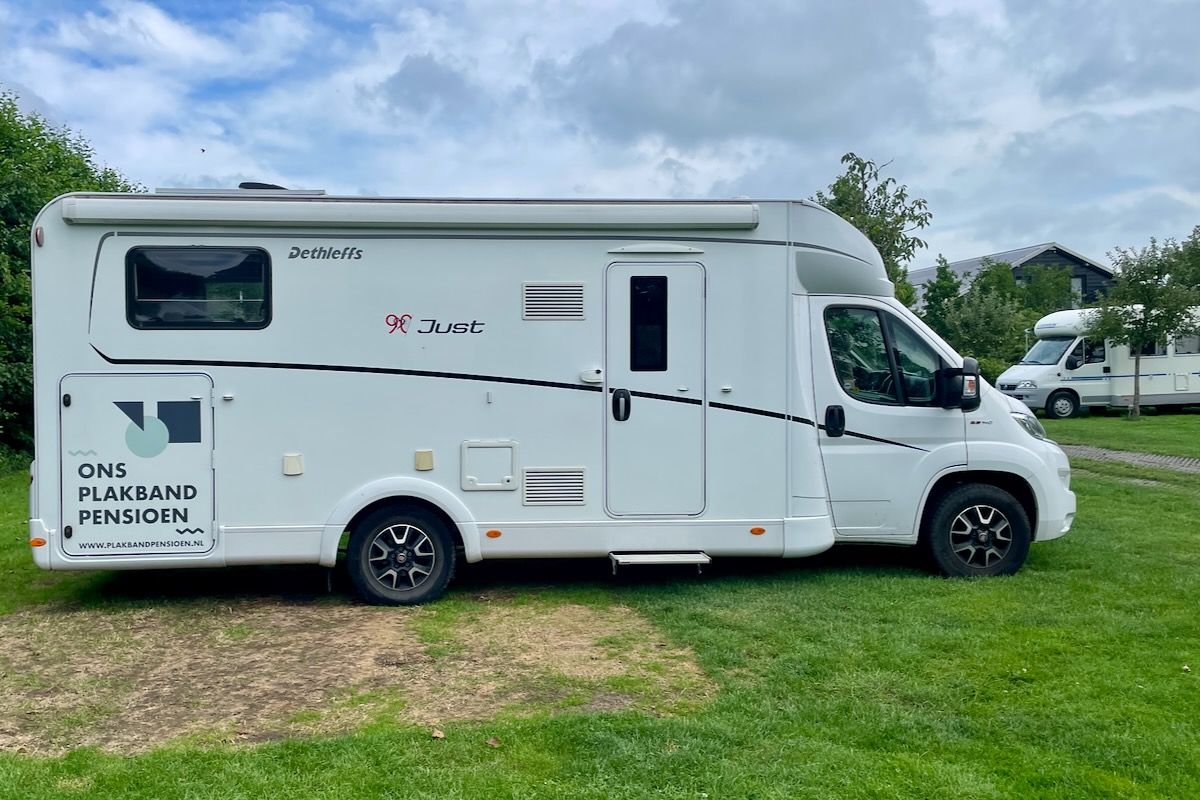 Een witte camper staat geparkeerd in een grasveld.