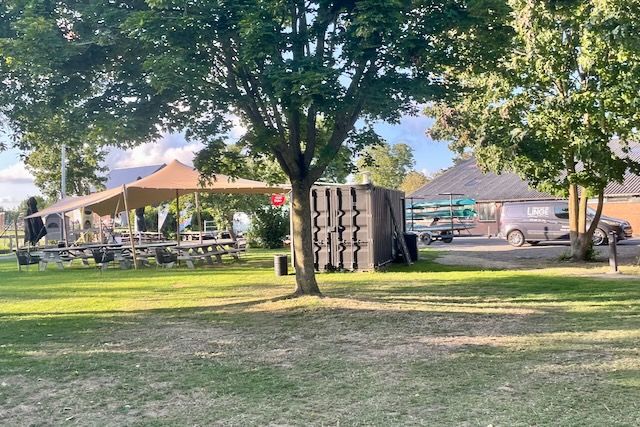 Een picknickplaats met tafels en parasols in een park.