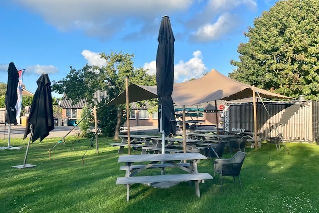 Een rij picknicktafels met parasols in een park