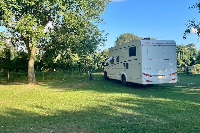 Een witte camper staat geparkeerd in een grasveld.