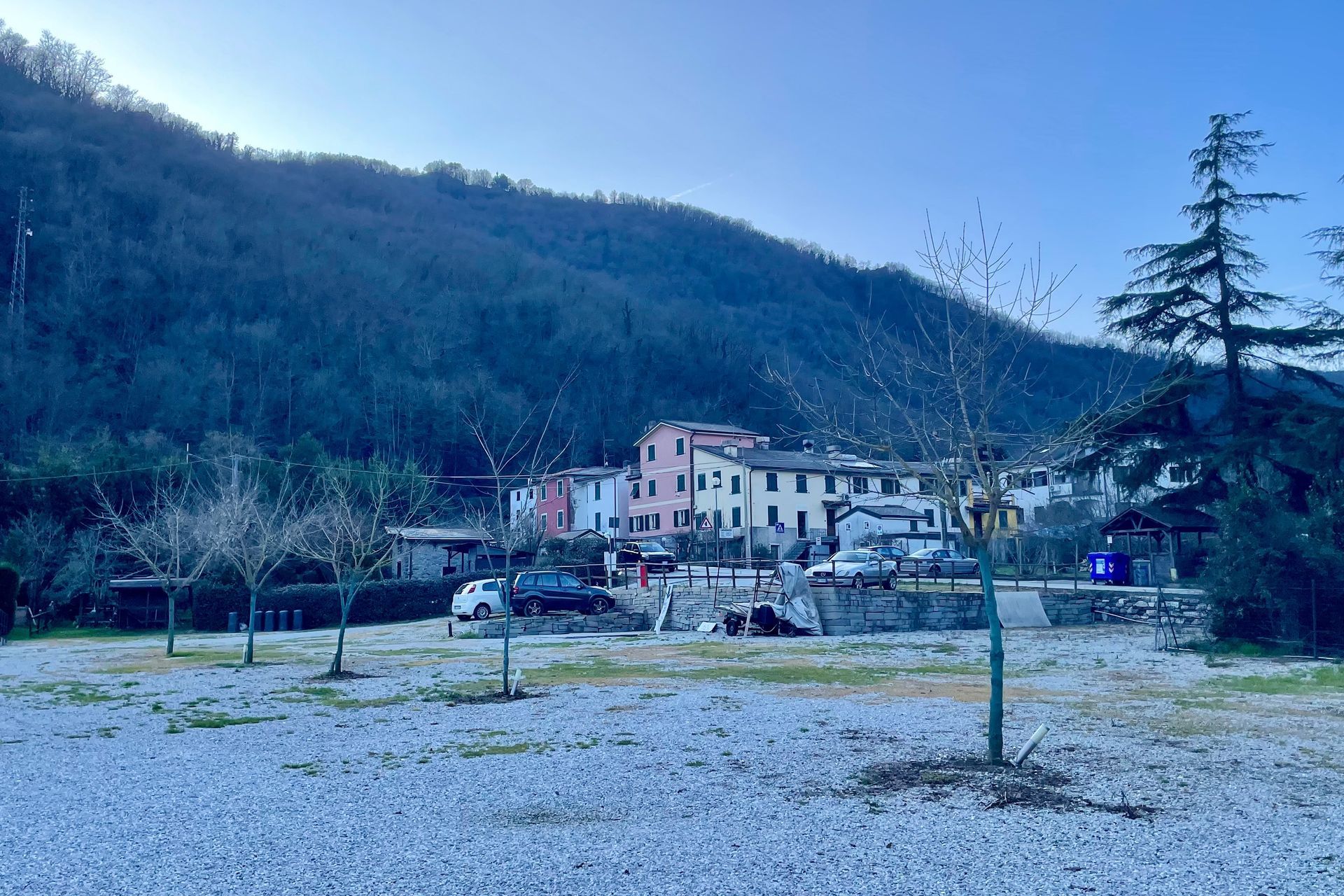 Italiaans Een stadje verscholen aan de voet van een beboste berg op een grijze dag. Kale bomen op de voorgrond.