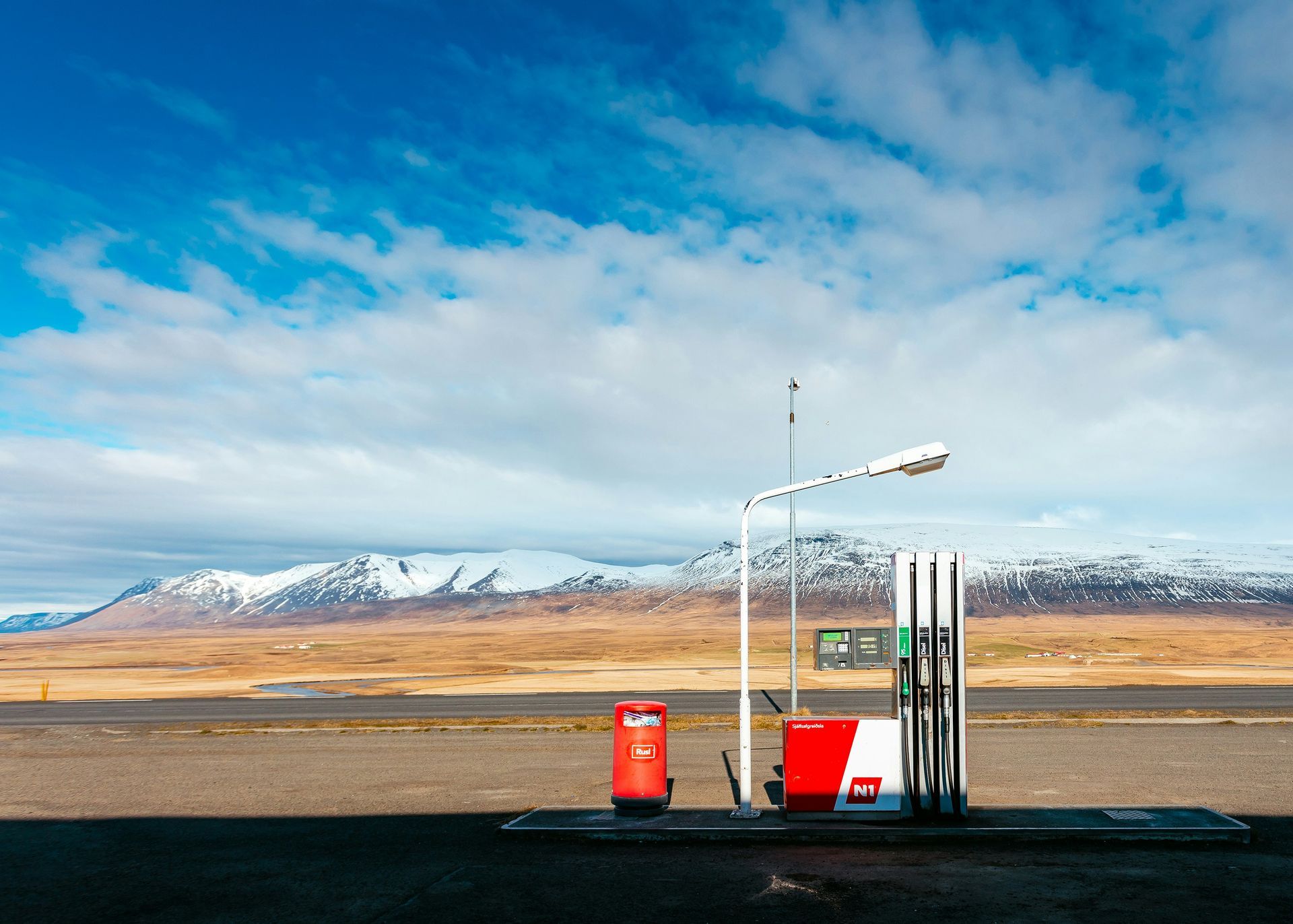 Een tankstation midden in de woestijn met bergen op de achtergrond.