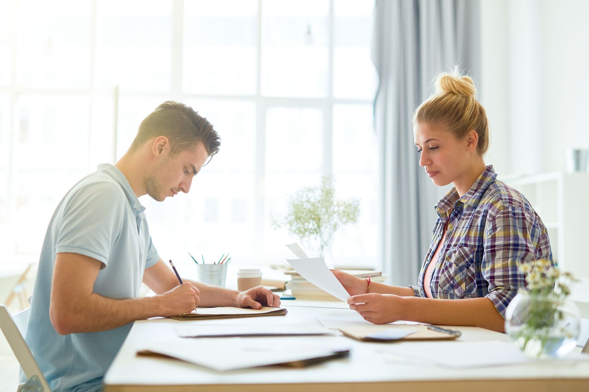 Two people reviewing papers at a bright table in an office setting