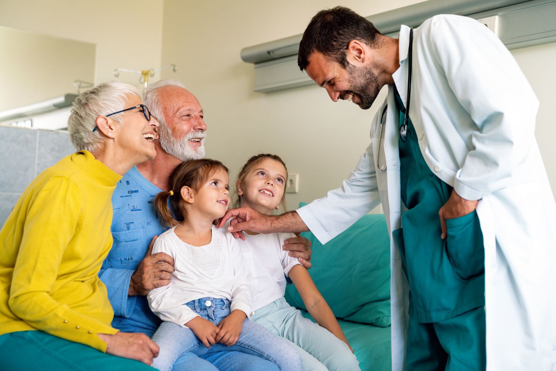 Doctor speaking with family in hospital room, smiling patients seated on a bed