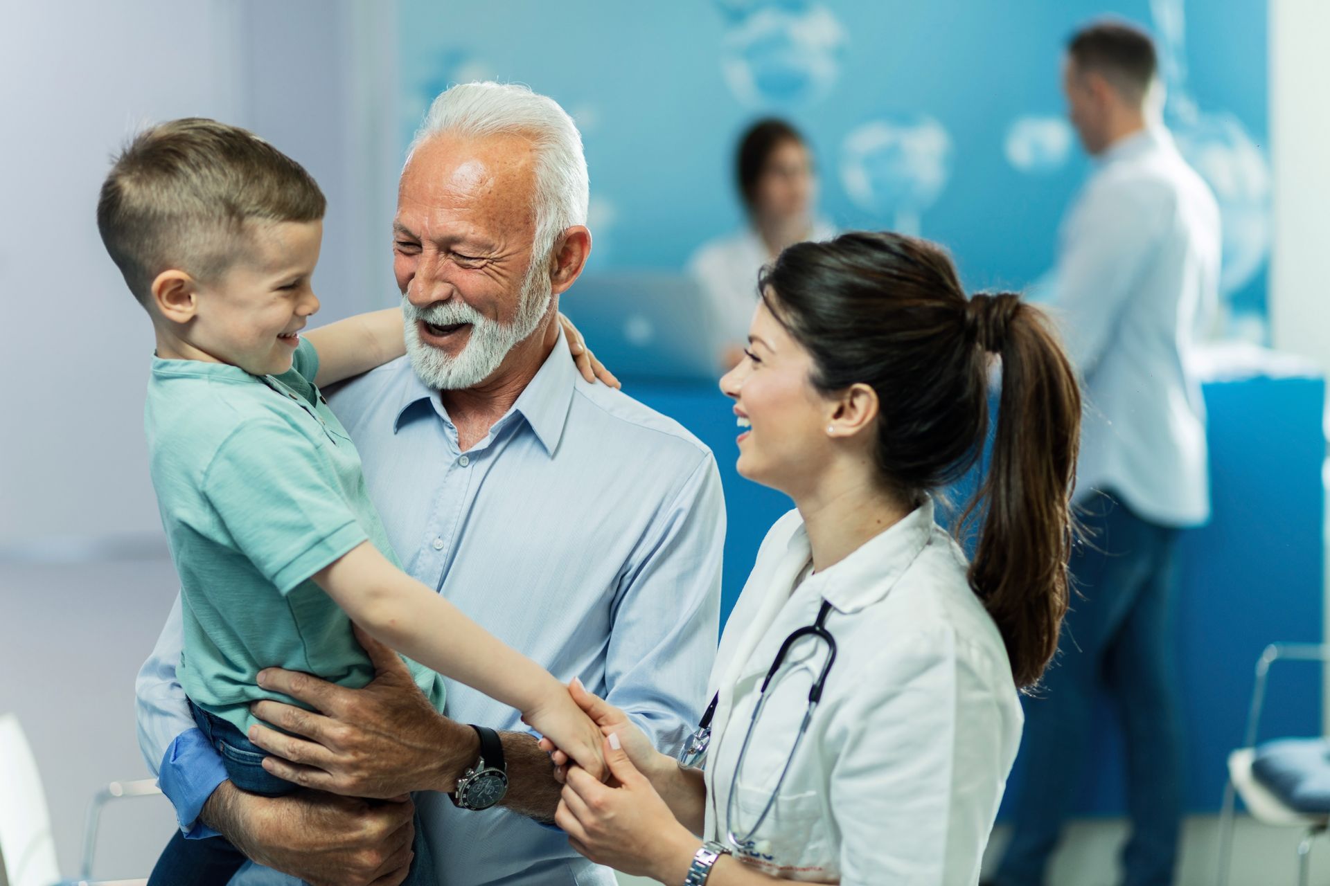 Doctor smiling with a child and older man in a clinic waiting area