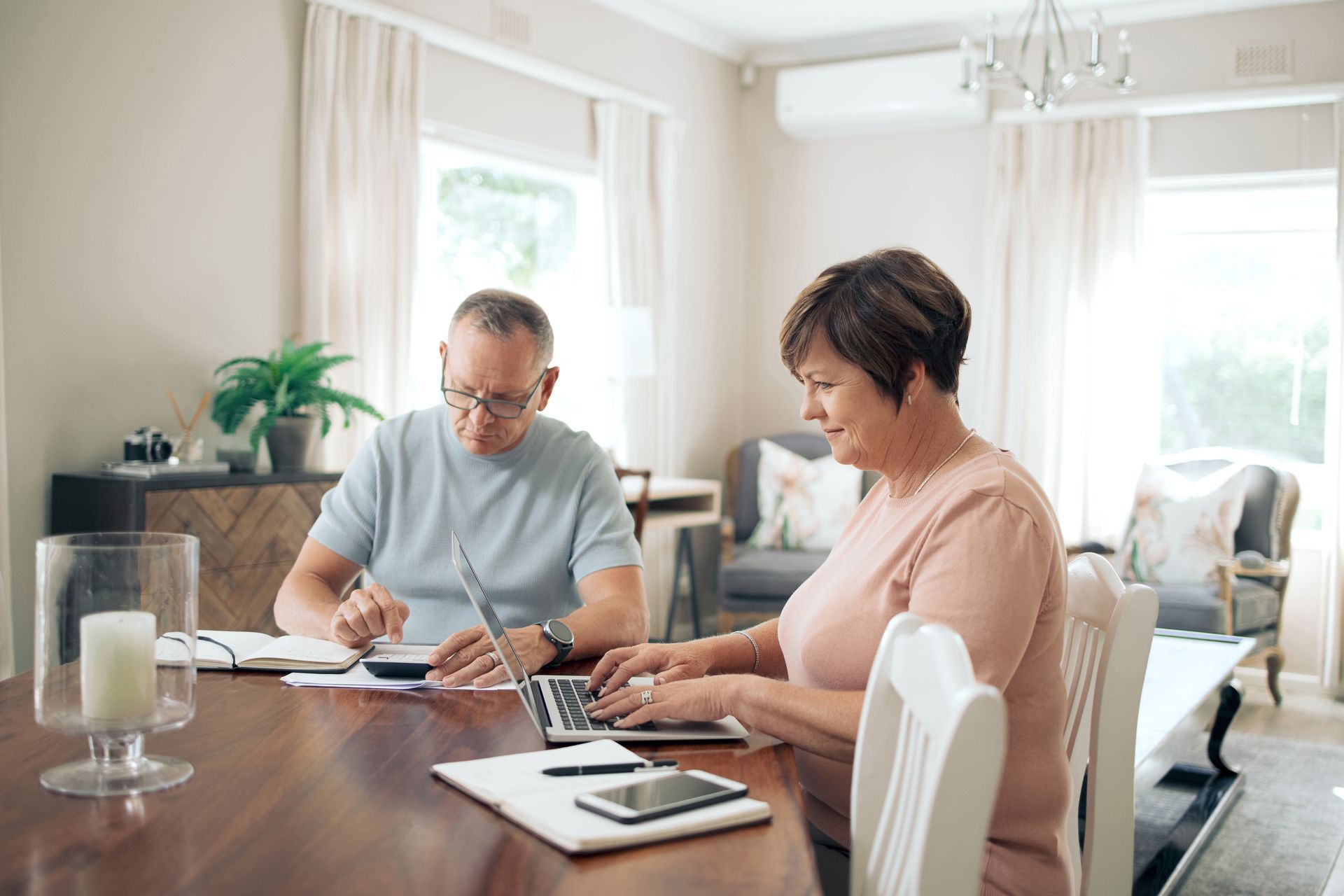 Two people reviewing paperwork at a dining table in a bright living room