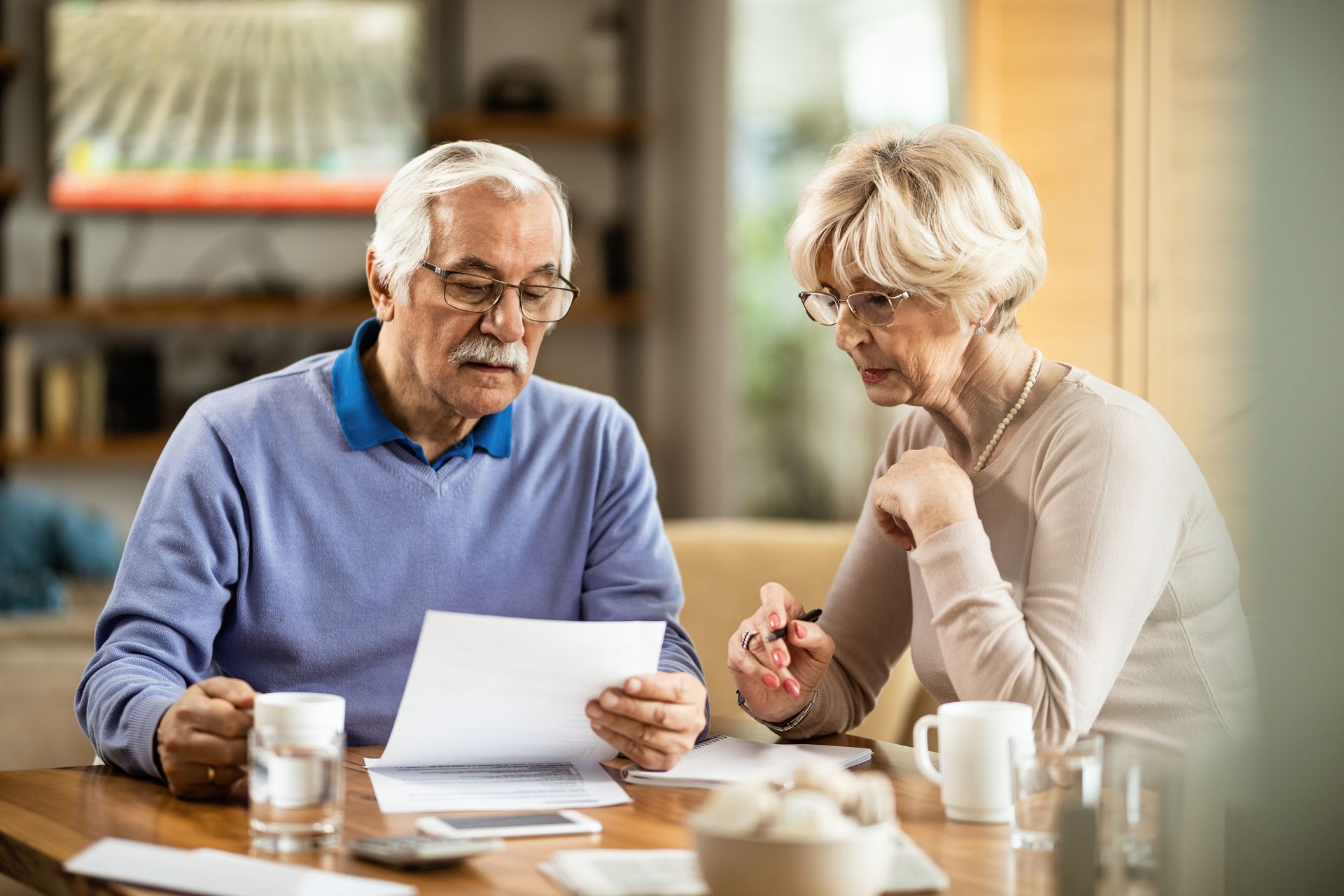 Two people reviewing papers at a café table, with coffee cups and a pen.