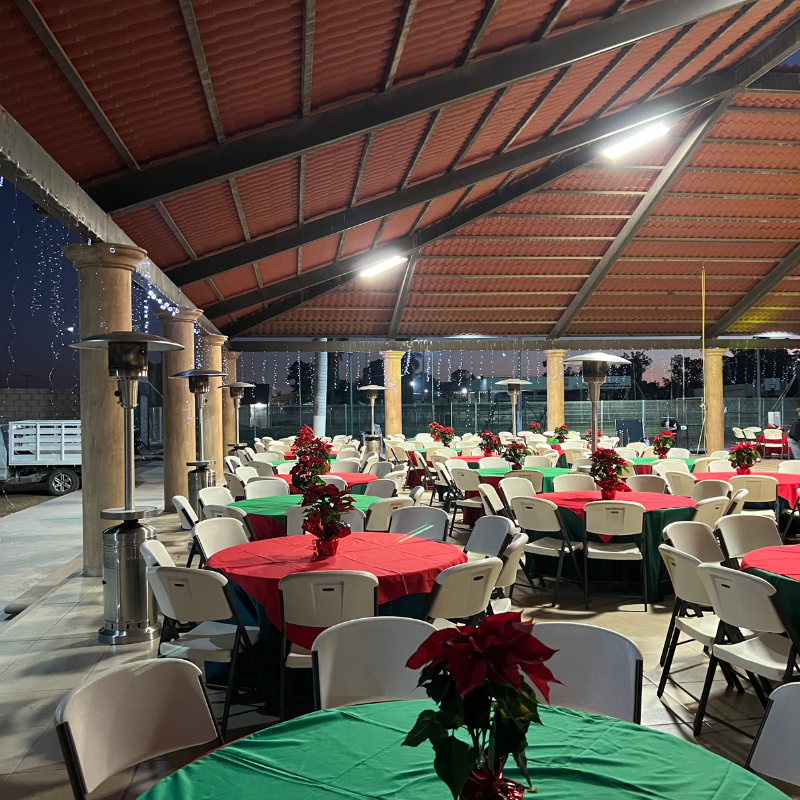 Un gran comedor al aire libre con mesas, sillas para fiesta y calentadores alrededor.