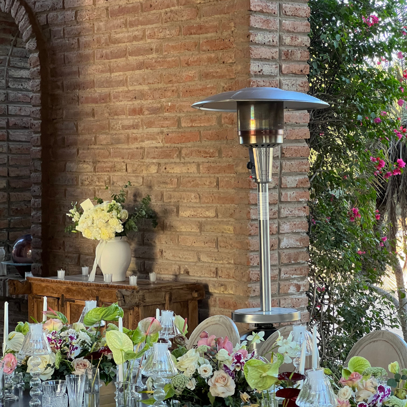 Una mesa con flores y velas y un calentador frente a una pared de ladrillos.