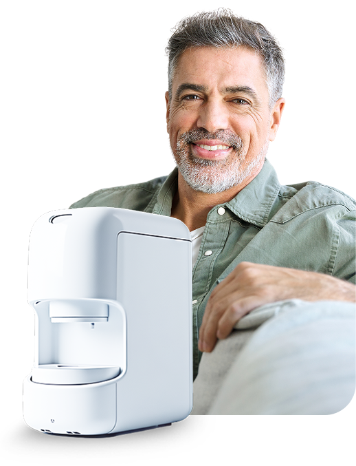 A man is sitting on a couch next to a coffee maker.