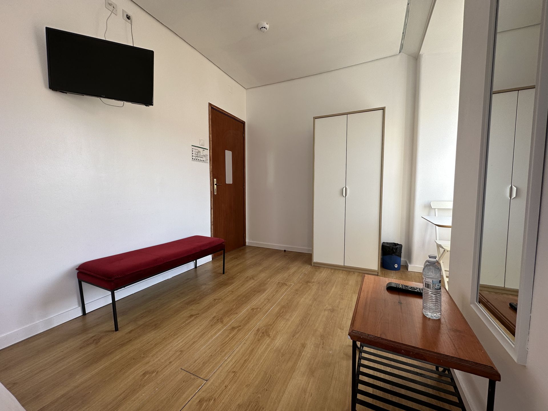 A room with a bench and a television on the wall
