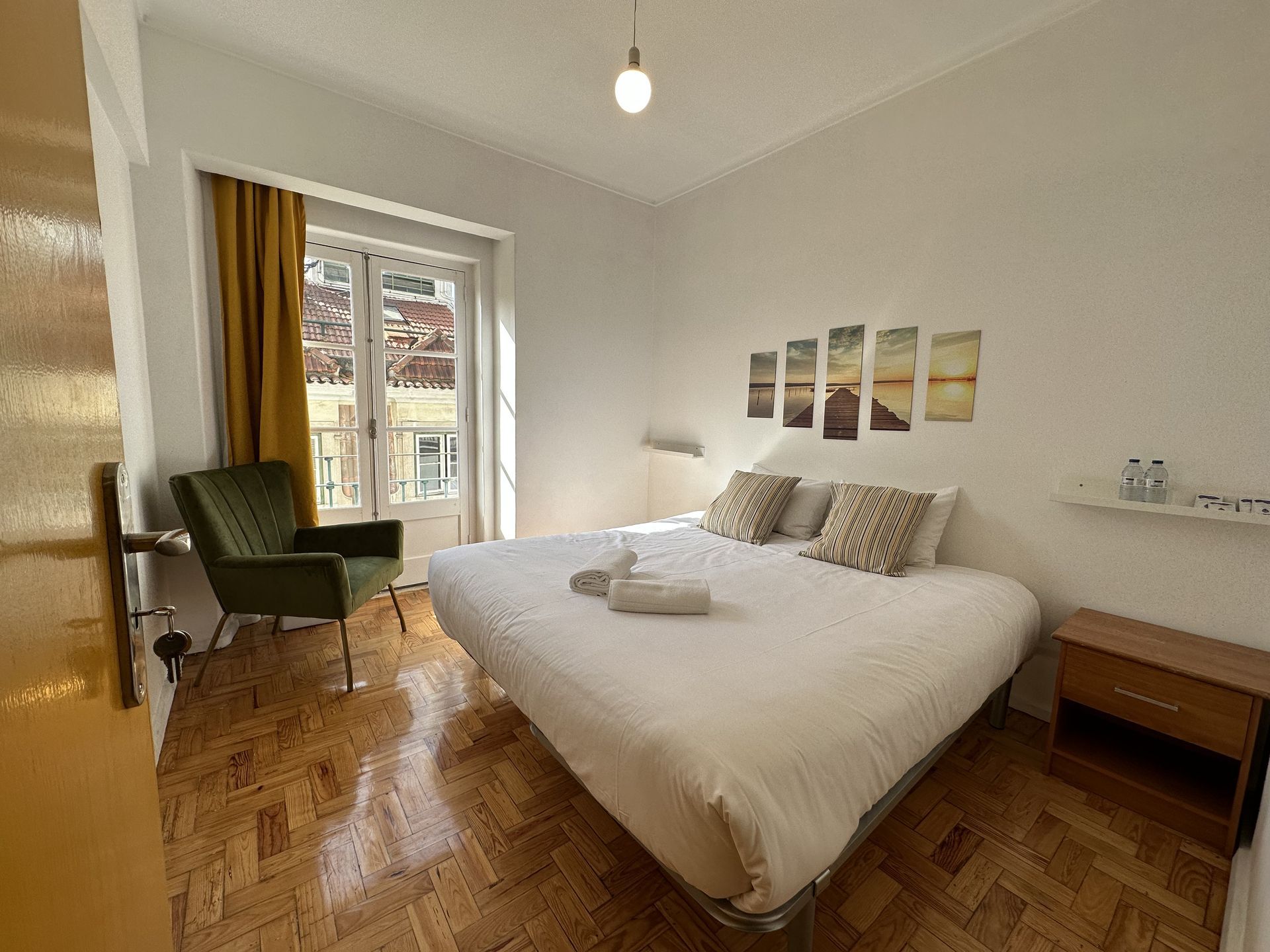 A bedroom with a bed , chair , nightstand and window.