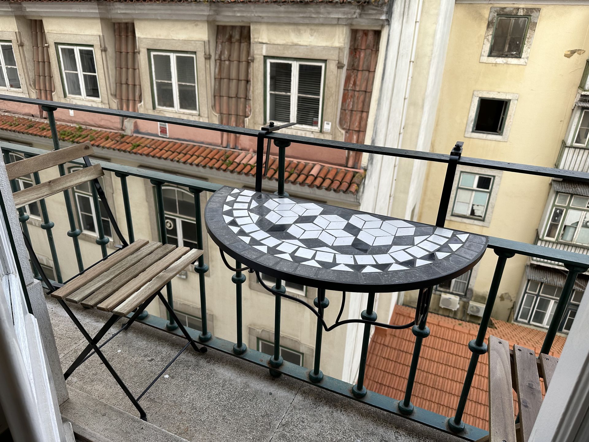 A balcony with a table and chairs and a view of a city.